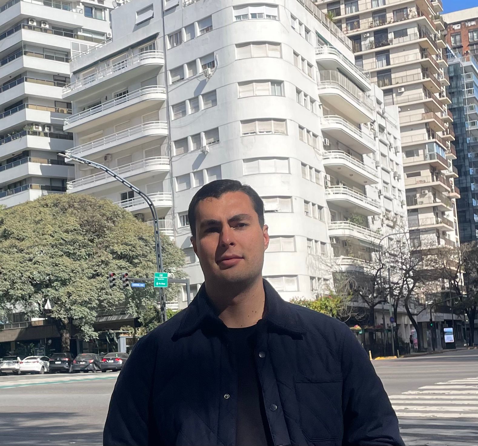 Facundo Franco standing on a city street, with white apartment buildings behind him.