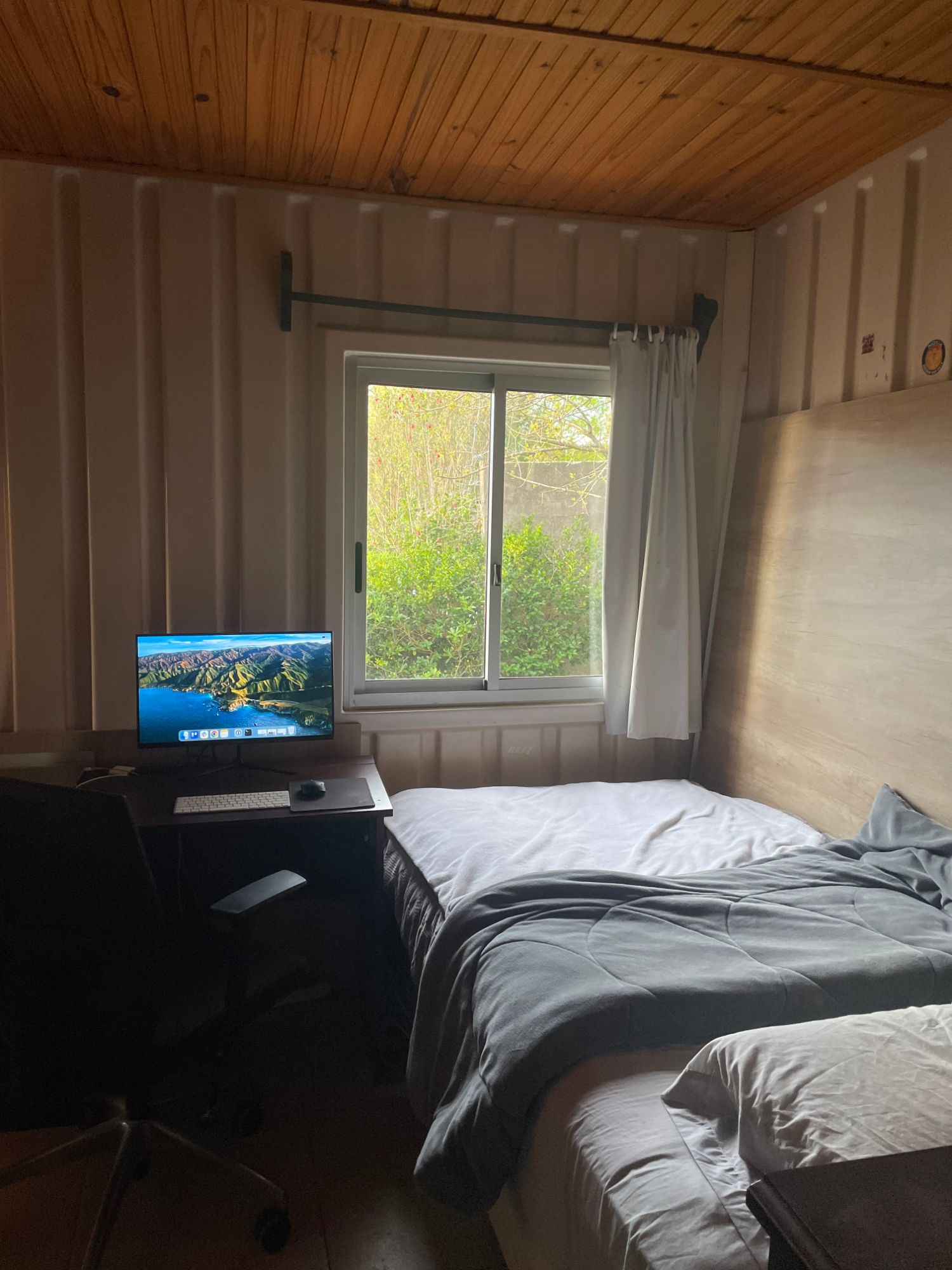 The small room where ScoutHalo was built: a desk with a computer and chair beside a bed, under a window.